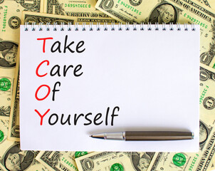 TCOY take care of yourself symbol. Concept words TCOY take care of yourself on white note on beautiful white background. Dollar bills. Business TCOY take care of yourself concept. Copy space.