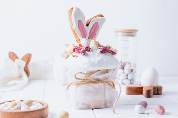 Fototapeta na wymiar Easter Panettone with bunny ears cookies, mini chocolate eggs, marshmallows and dry roses.