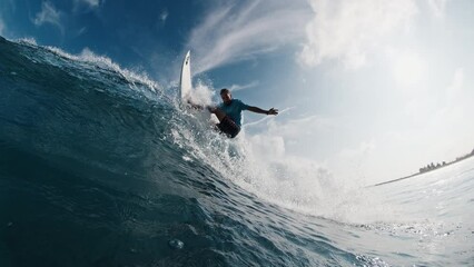 Pro surfer rides the wave. Young man surfs the ocean wave in the Maldives and aggressively turns on the lip. Splitted above and underwater view