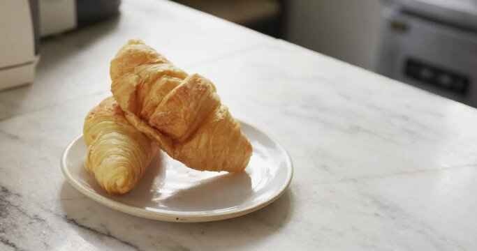 Close up of two croissants on white plate on countertop at cafe