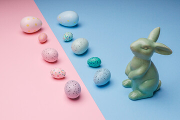 Easter eggs on a pink and blue background and a rabbit