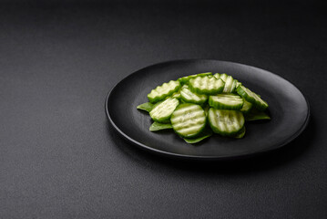Delicious healthy raw cucumber sliced ??on a black ceramic plate
