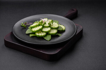 Delicious healthy raw cucumber sliced ??on a black ceramic plate