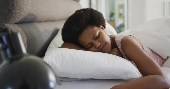 Happy african american woman laying in bed, sleeping in bedroom