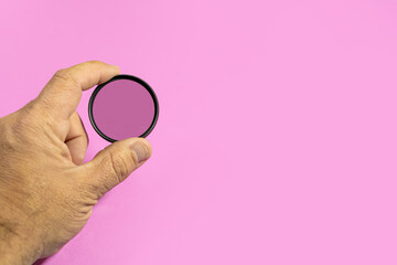 Male hand showing a ND filter for photographic lens on a purple background