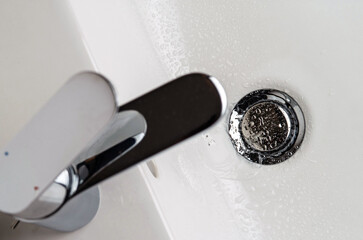 A stream of clean water pours from the tap into the sink. Selective focus.