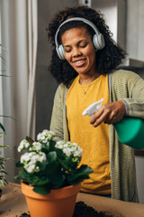African American woman sprays flowers with sprinkler