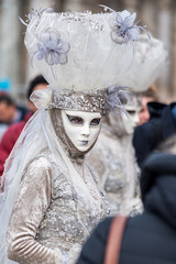 Beautiful candid white carnival mask. Mask that looks at me with blue eyes, covered in pearls and flowers. Venetian masks with sensuality and extravagance.