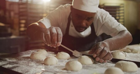 Animation of focused african american male baker preparing rolls - Powered by Adobe