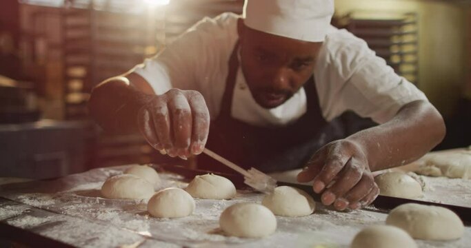 Animation of focused african american male baker preparing rolls