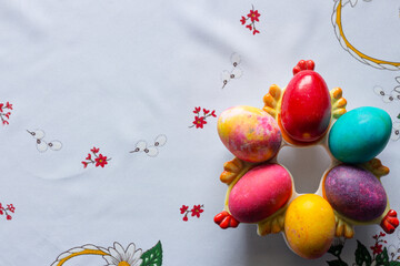 Top view of colored easter eggs on a white tablecloth