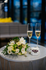 Before the wedding ceremony at the registry office decoration composition: wedding rings for the bride and groom in a box on the table next to the wedding bouquet and two glasses of champagne