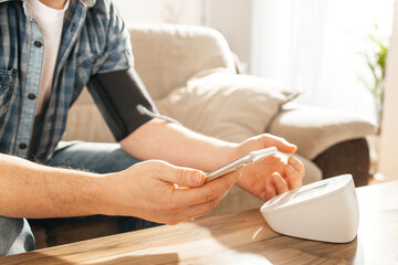 A man measures his blood pressure at home using a tanrometer and a measuring cuff. The concept of...