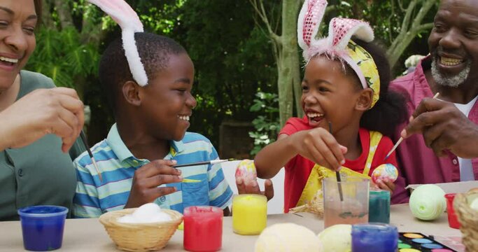 Animation of happy diverse grandmother and grandchildren painting easter eggs in garden