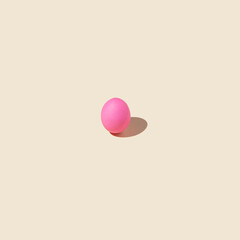 Minimal pink Easter egg on bright yellow background. Flat lay.