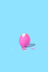 Peeled pink easter egg on blue background. Minimal creative concept.