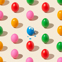 Pattern made of colored eggs on pastel yellow background with one peeled egg. Minimal food concept.