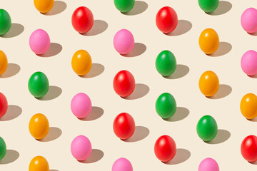 Pattern made of colored eggs on pastel yellow background. Minimal food concept.