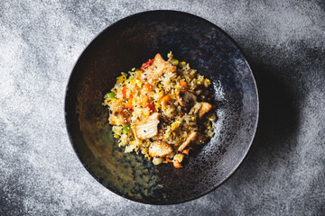 Rice with seafood and vegetables in a beautiful plate on a dark textured background