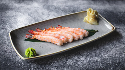 Shrimps on a leaf in a stylish plate on a dark background. Asian food.