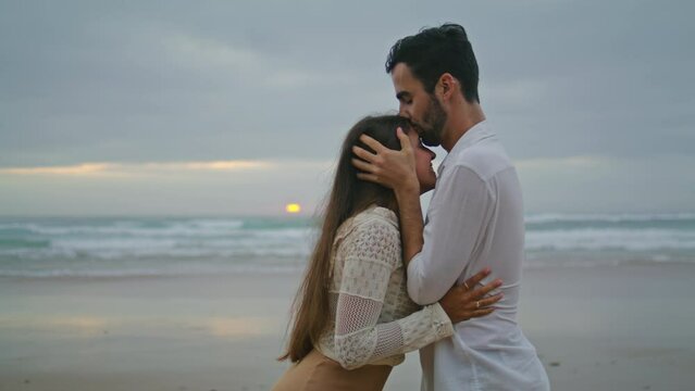 Carefree newlyweds cuddling evening beach closeup. Smiling man kissing woman