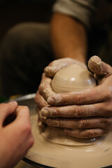 Man hands holding and makes a mold out of clay on pottery wheel. Workshop, closeup