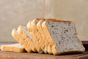 Sliced rectangular loaf of bread with flax grains on a wooden cutting board