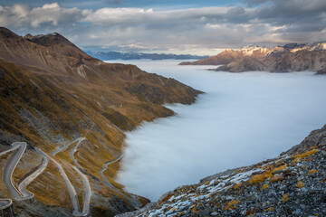 Stelvio pass, mountain dramatic landscape at dawn above mist, Italy