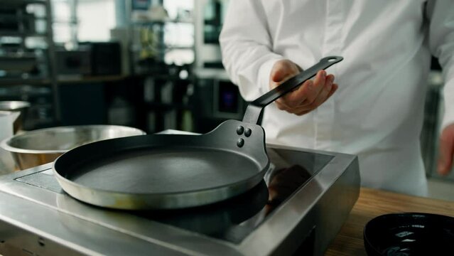 Professional kitchen - chef checking a pan for cooking pancakes. Professional stove