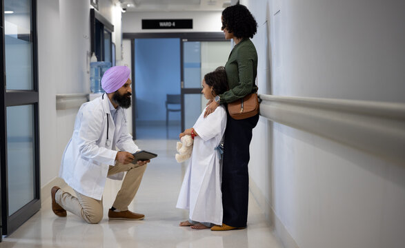 Sikh male doctor in turban talking with daughter and mother embracing in hospital
