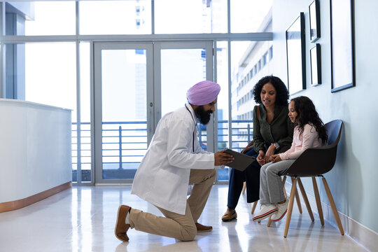 Sikh male doctor in turban talking with daughter and mother in hospital
