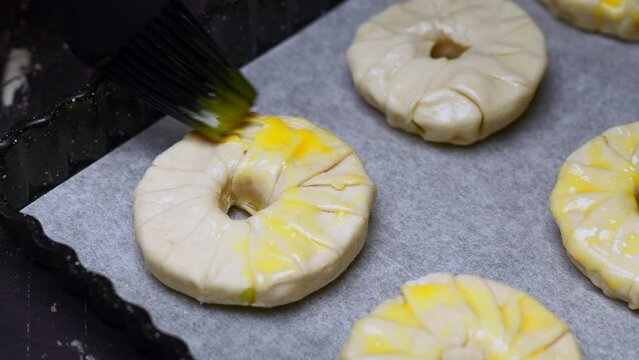 the chef with a black brush smears pastries with egg yolk before cooking on a pan. High quality 4k footage