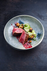 Fried Italian chianina beef fillet steak very rare with mushrooms, zucchini and amarena sauce served as close-up in a Nordic design bowl