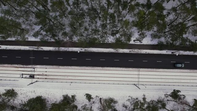 Car driving Aerial view on road in winter time, road surrounded with forest trees. Rural winter area. Top view landscape. shooting from drone. Snow covered road in winter forest. Road seen from the