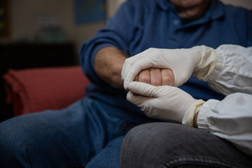 Close-up of a doctor's hands holding the hands of an elderly patient