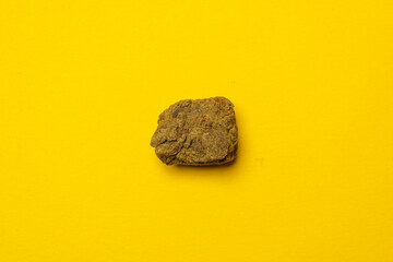 Piece of high quality dry sift hashish isolated on a yellow background. Medical marijuana extraction hash cannabis pollen hashish