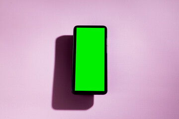 Smartphone with green screen on top of a pink table. smartphone concept. Green screen concept.