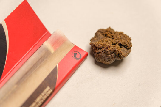 Rolling papers with a piece of high quality Moroccan hashish on white backgroung