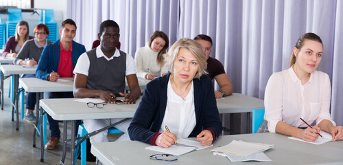 Fototapeta na wymiar Portrait of attentive adult students on training session in auditorium .