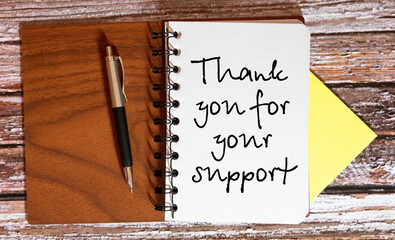 On the table there is a pen, clamps and a notebook with the inscription - THANK YOU FOR YOUR SUPPORT