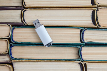 USB flash drive of a computer on the background of a stack of old paper books