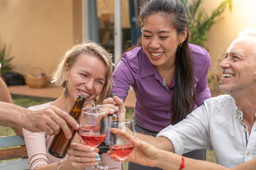Close-up of a group of cheerful friends toasting with beautiful smile around the table at house patio diner. High quality photo