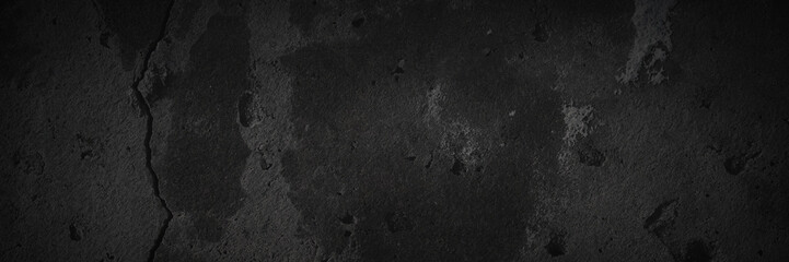Texture of old cracked concrete wall. Rough dark gray concrete surface with spots, cracks, noise and grain. Dark wide panoramic background for design. Shaded texture with vignette.