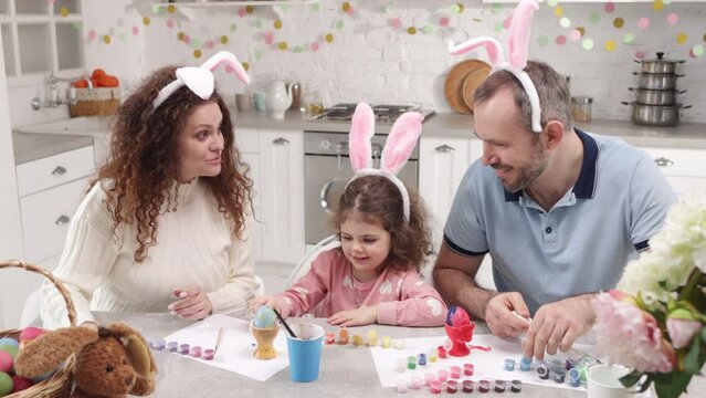 Religious mother and father enjoying festive season together. Portrait of caucasian family with little, cute daughter wearing bunny ears and taking pictures. High quality 4k footage