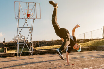 teenager boy dancing breakdance on a basketball court. hip hop culture. street and youth culture....
