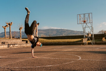 teenager boy dancing breakdance on a basketball court. hip hop culture. street and youth culture. street dancer.