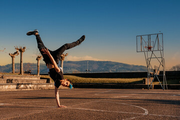 teenager boy dancing breakdance on a basketball court. hip hop culture. street and youth culture....