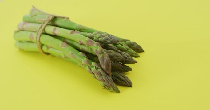 Video of close up of bundle of fresh asparagus over green background