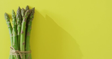 Video of bundle of fresh asparagus with copy space over green background