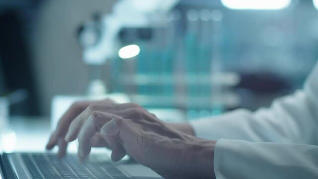 Close up shot of young female scientist typing on laptop at desk in laboratory